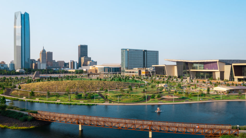 Scissortail Park in Oklahoma City, Oklahoma is featured in warm afternoon light. The Oklahoma City Omni Hotel and Oklahoma City Convention Center can be seen in the background.