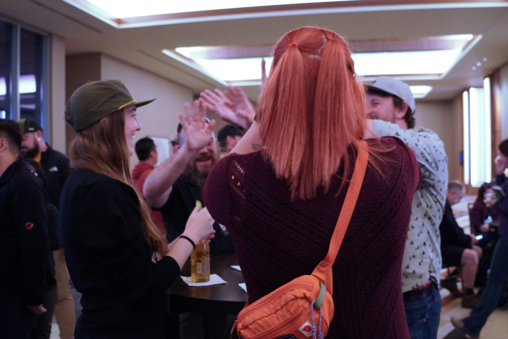 Four people exchange a group high five as they get excited about the annual conference and exposition during a Cocktail Reception before the Opening Ceremony.