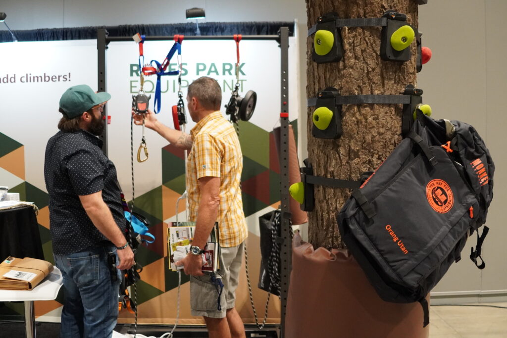 An attendee examines a piece of equipment while an exhibitor answers their questions in the Exhibit Hall.