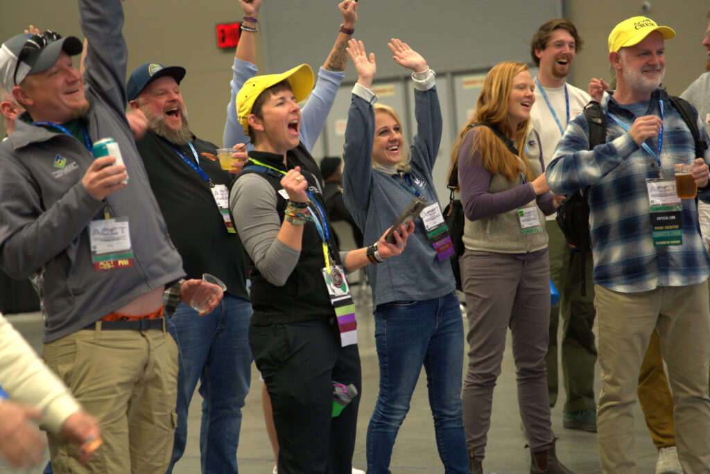 A crowd of onlookers cheers after someone wins the human slot machine at the ACCT booth in the Exhibit Hall at the 2025 conference and exposition.