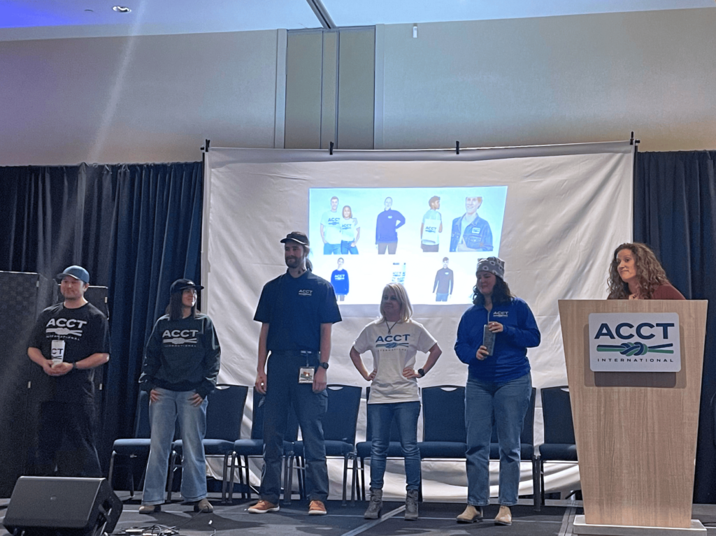 Members of the Public Relations and Marketing Work Group as well as the Conference Work Group and Service Crew model the new merchandise available at the new online ACCT International merch store during the Opening Ceremony at the conference and exposition in 2025.