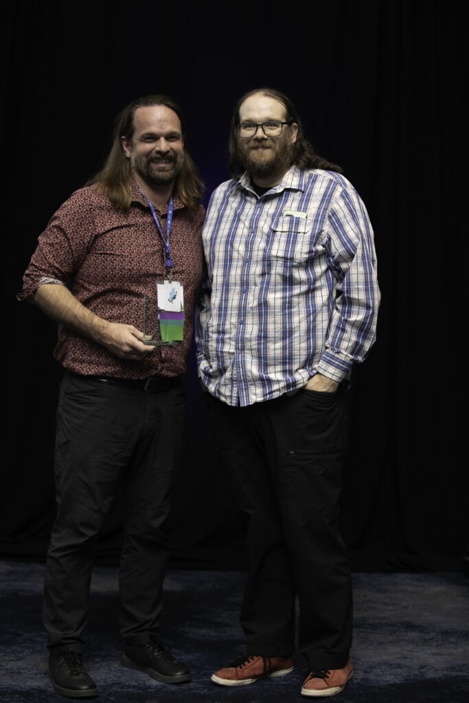 Dan Harbuck holds a Community Service Award while standing alongside John Voegtlin, who recognized Dan's volunteer efforts in 2024 during the Awards Ceremony hosted at the 2025 ACCT conference and exposition.