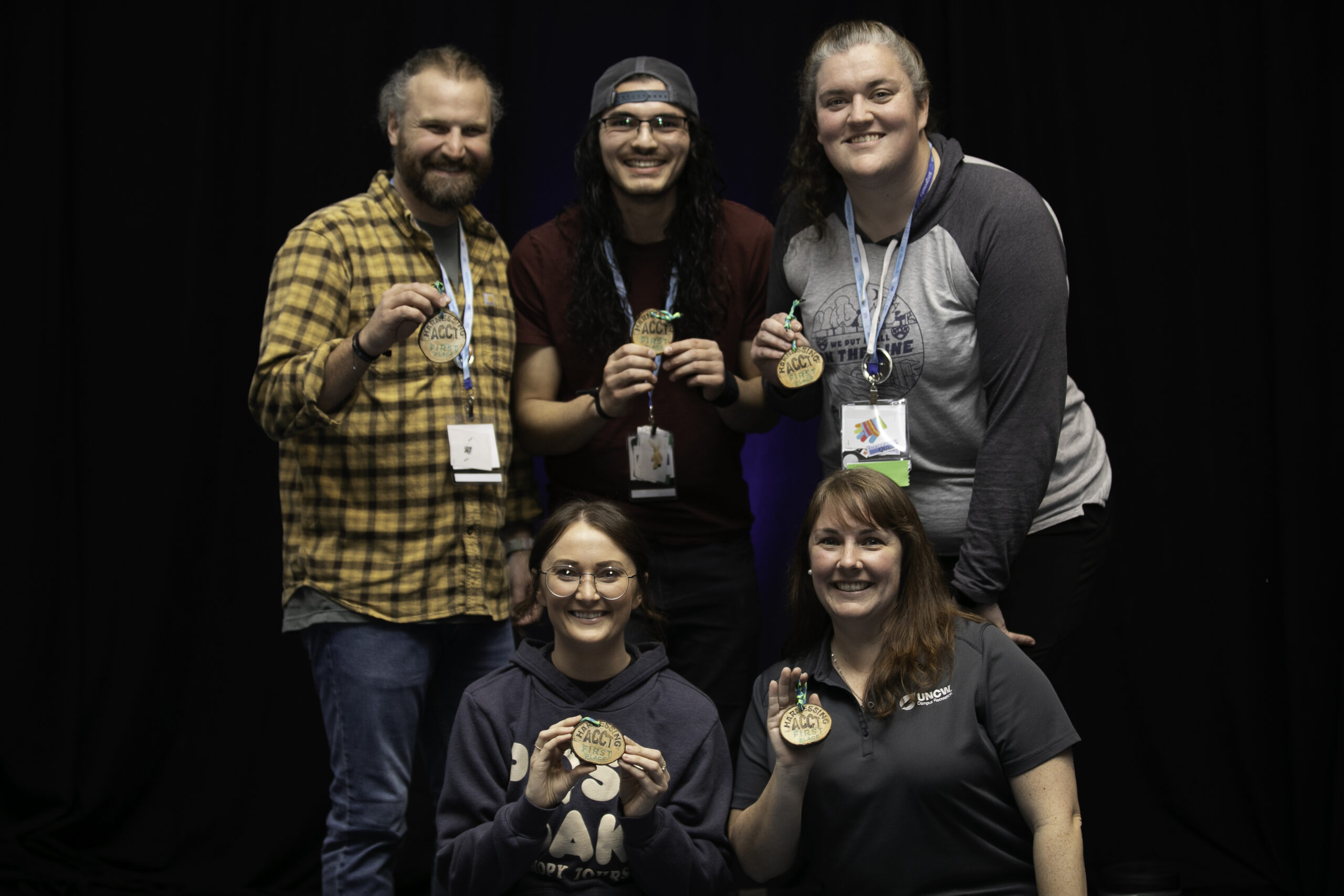 Five members of the Pawpaw Posse smile together while holding wood cookies that read "Harnessing ACCT First Place" during the Awards Ceremony at the 2025 conference and exposition.