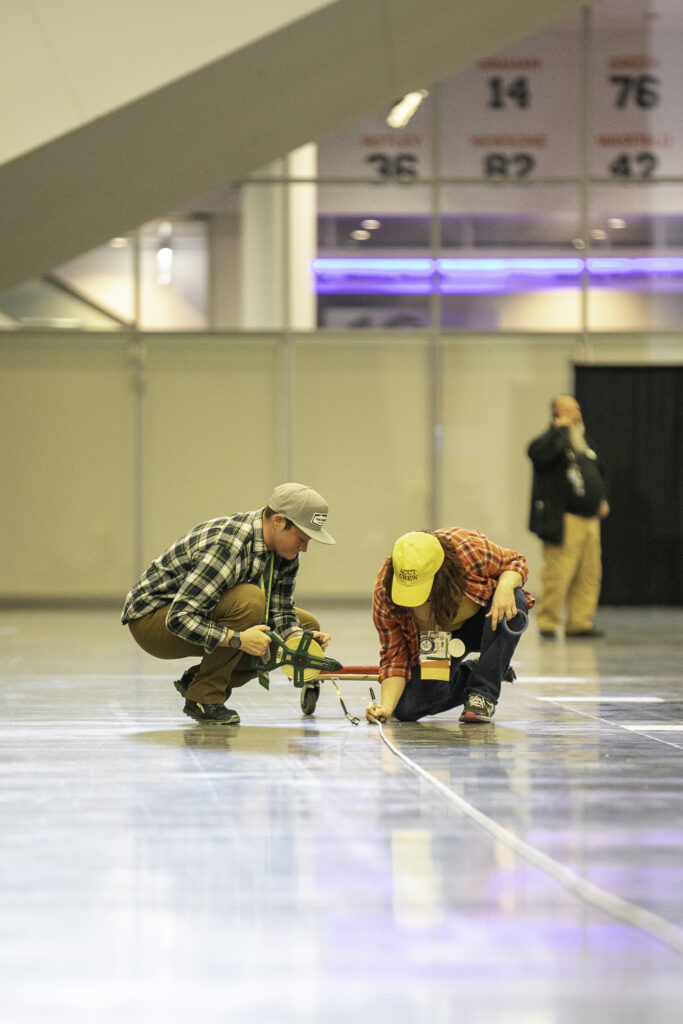 A member of the Conference Work Group and a member of the Service Crew measure the distance a participant of the cable whip event successfully whipped the cable during the Harnessing ACCT showdown hosted at the 2025 conference and exposition.