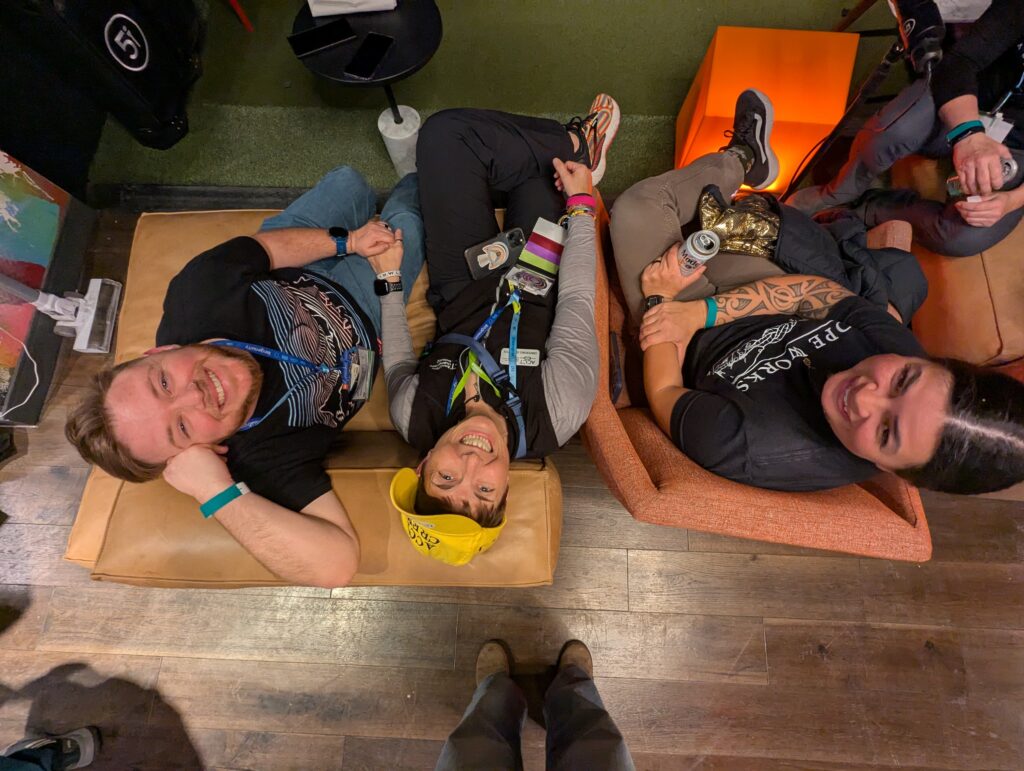 Three people smile up at the camera while sitting in cushioned chairs at Five Iron Golf during the After Hours Social sponsored by Granite Insurance during the 2025 ACCT conference and exposition.