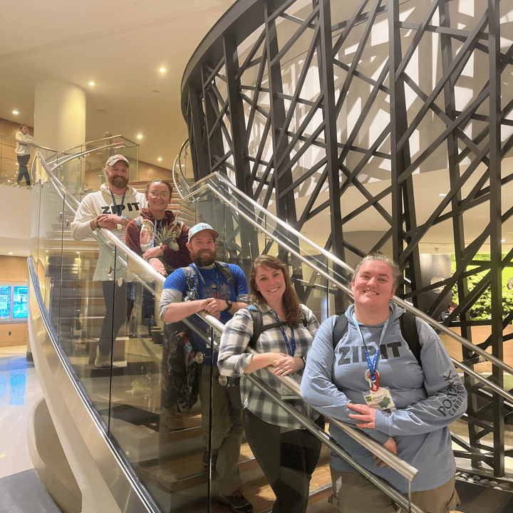 Five members of the Harnessing ACCT team Pawpaw Posse smile on the staircase of the Hilton Downtown Cleveland, the host hotel for the 2025 conference and exposition.