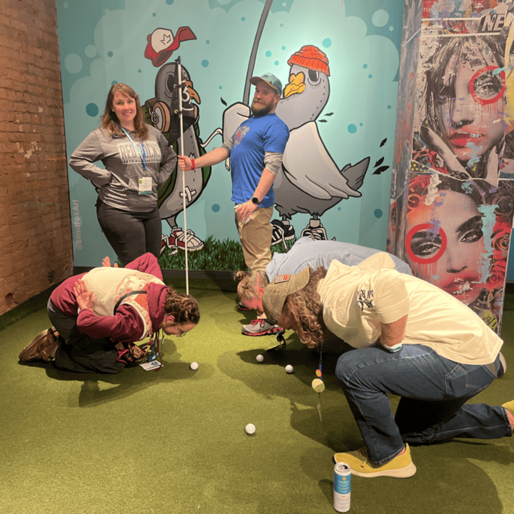 Five members of the Pawpaw Posse pose in silly ways at a golf hole at Five Iron Golf, where Granite Insurance hosted a sponsored After Hours Social during the 2025 conference and exposition.