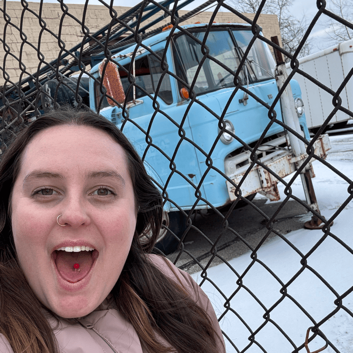 A member of the Harnessing ACCT team Polka Dot Dynamos smiles with a vintage truck in the background as part of a Harnessing CLE challenge during the 2025 conference and exposition.