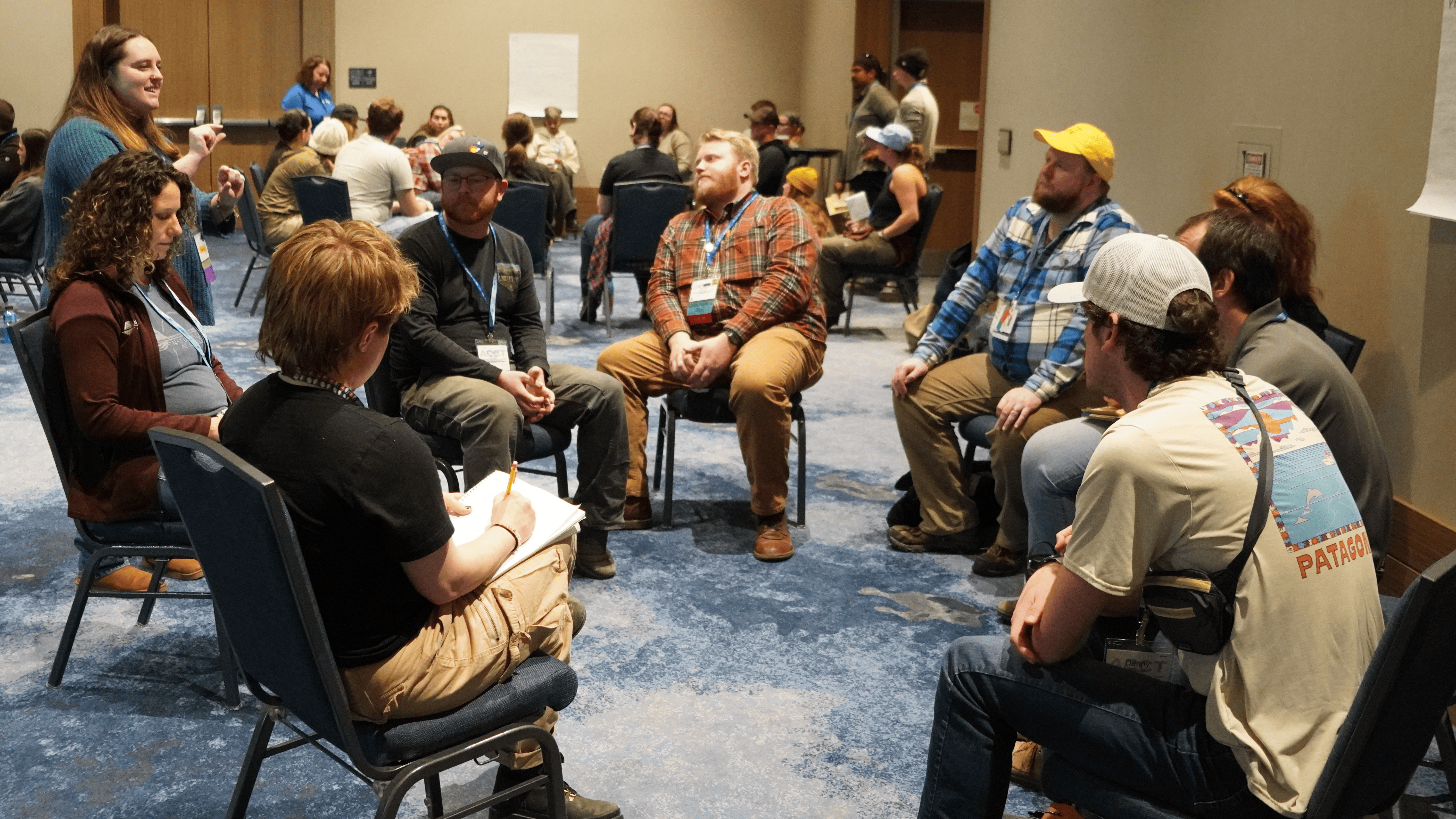 A circle of attendees sitting in chairs listen to a presenter while meeting in small groups during the 2025 ACCT conference and exposition.