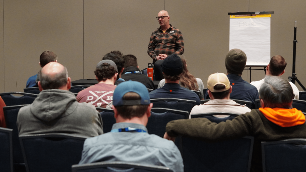 A presenter stands as they address a crowd of attendees sitting in chairs during the 2025 ACCT conference and exposition.