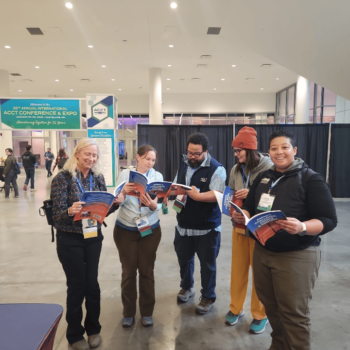 Five members of the Harnessing ACCT team Trillium Troublemakers read a book in the Exhibit Hall during the 2025 conference and exposition.