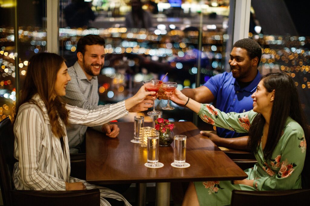 Four people cheers during drinks at a bar and restaurant in Oklahoma City, OK.