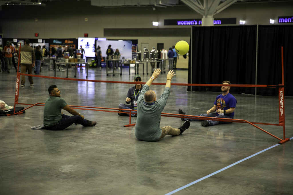 Four people play sitting volleyball, hosted by the Universal Design, Accessibility and Inclusion ACCT Affinity Group, in the Exhibit Hall at the 2025 conference and exposition.