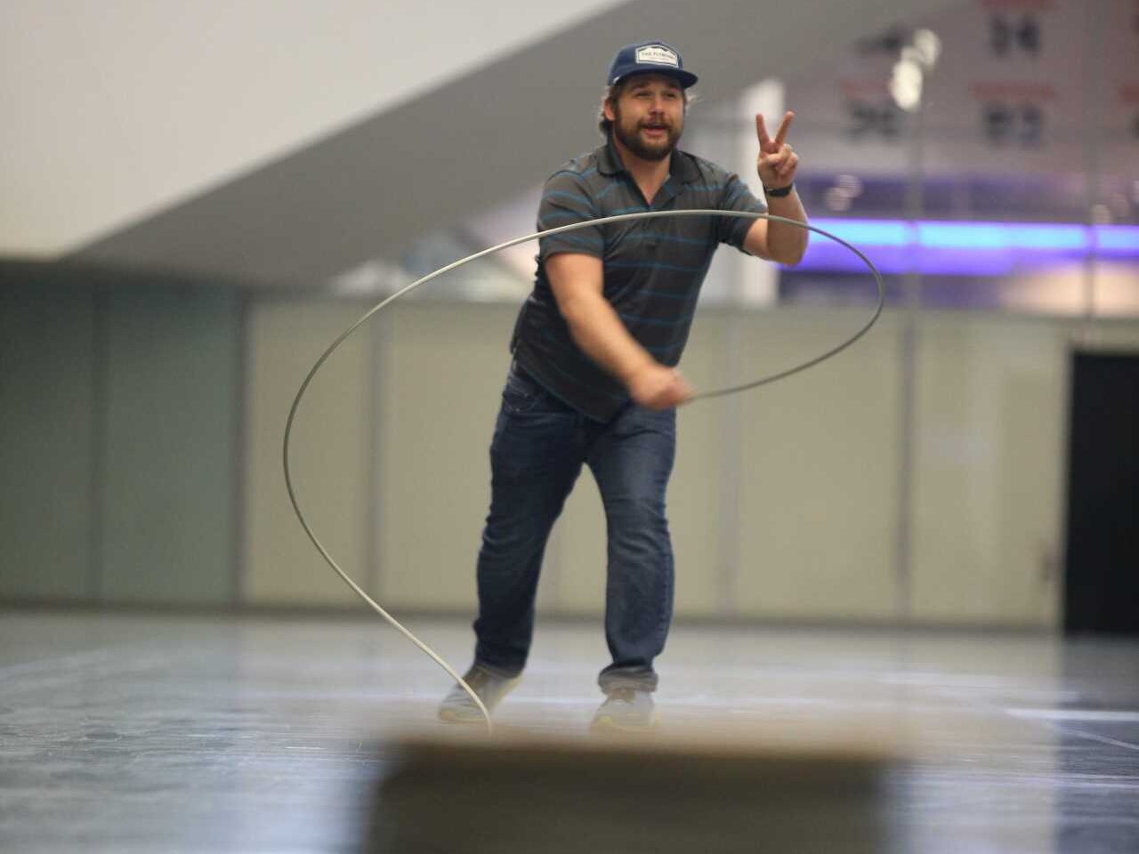 A man shows a peace sign while expertly whipping galvanized steel aircraft cable during the Harnessing ACCT showdown hosted at the 2025 conference and exposition in the Exhibit Hall.