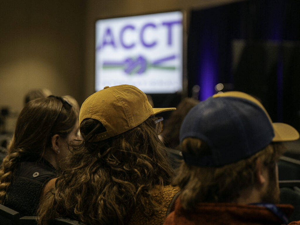 The new ACCT International brand logo is seen on a large projector screen behind the heads of attendees of the Opening Ceremony, when the new logo was publicly unveiled.